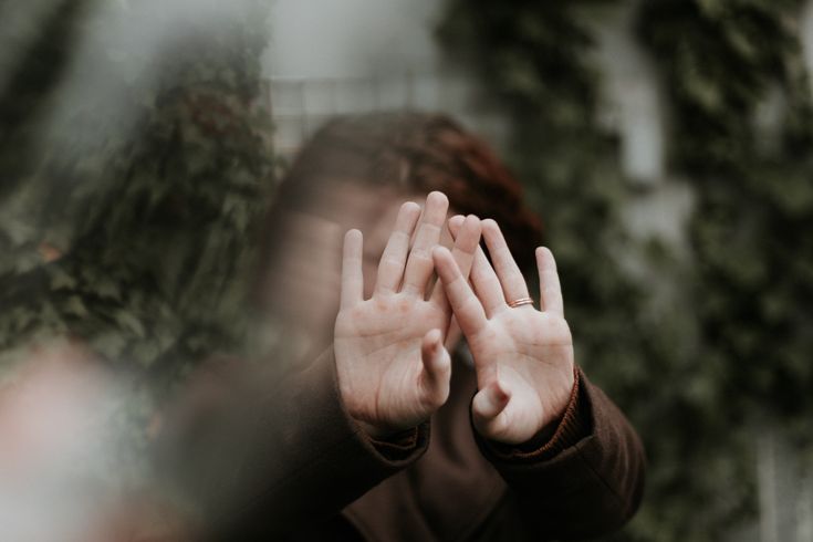 Attachement insécure – douleur relationnelle Femme seule assise, visage caché dans ses mains, sur fond flouté sombre, illustrant la douleur liée à un attachement insécure